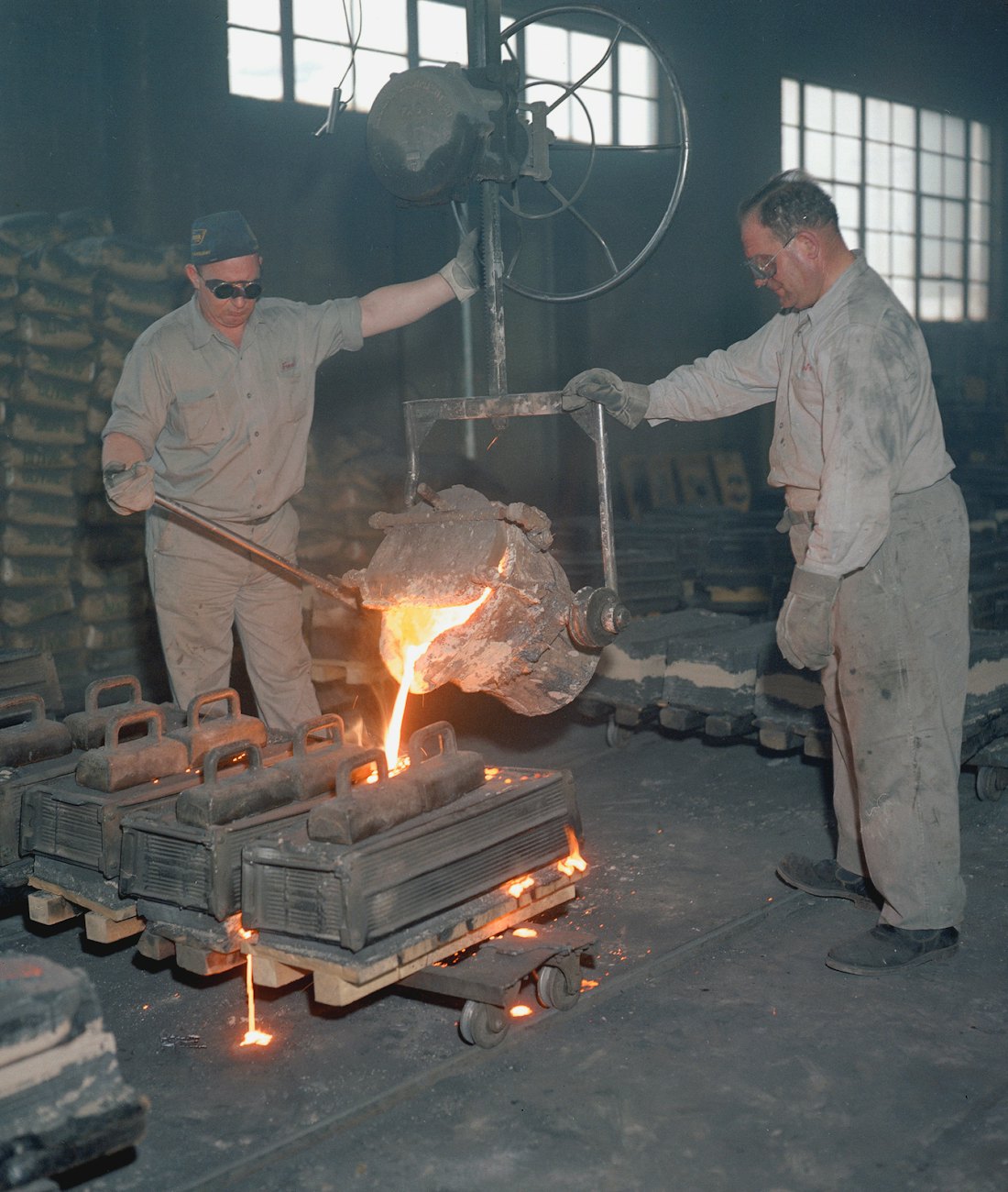 Foundry workers pouring molten metal into ingot moulds on the casting floor