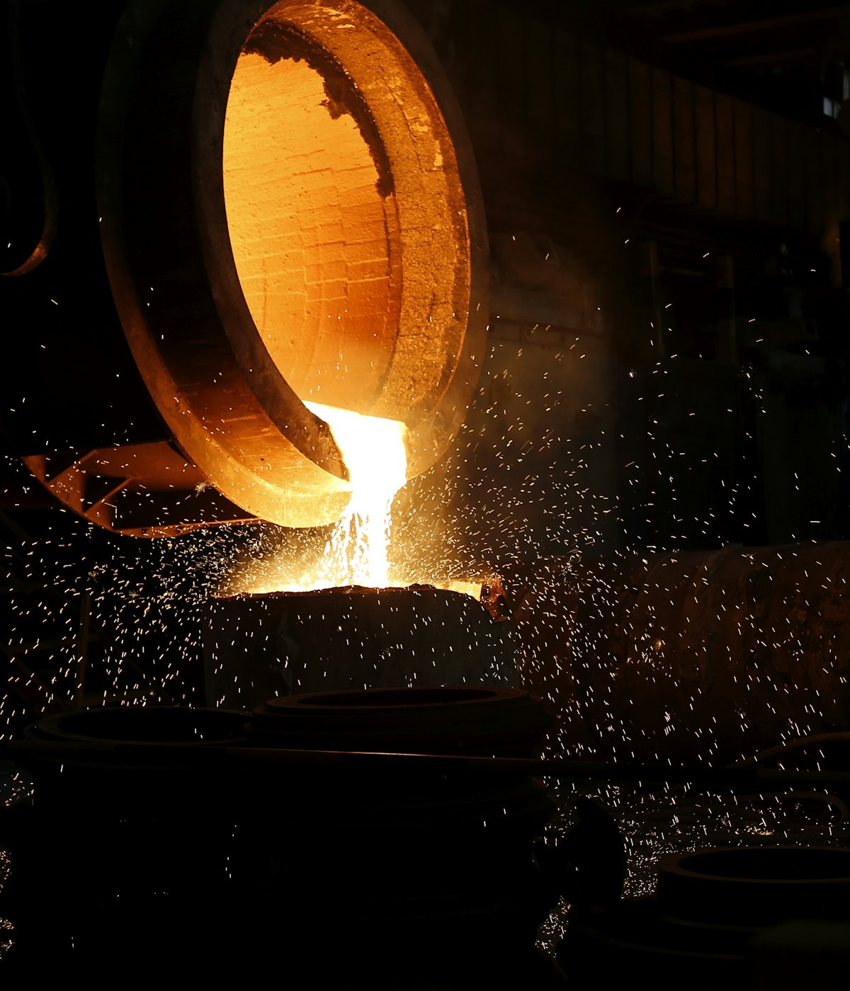 Molten aluminium pouring from a foundry ladle in a shower of sparks