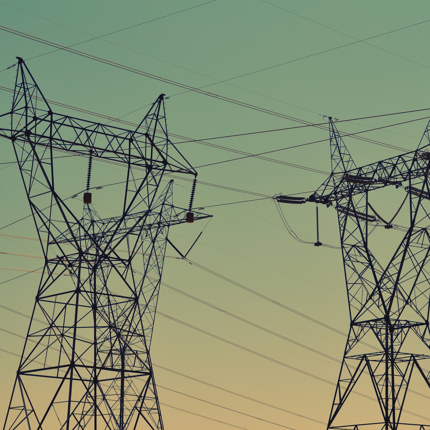 High-voltage transmission towers carrying aluminium conductor lines against an evening sky